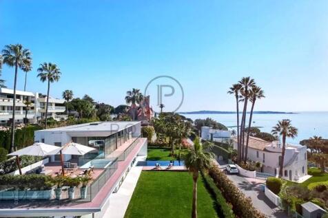 Modern coastal houses with palm trees, a pool, and