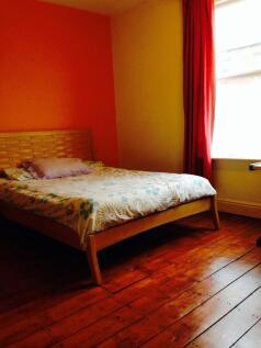 A cozy double bedroom featuring a wooden bed fr...