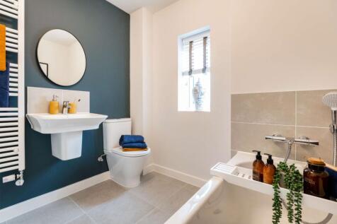 A modern bathroom features a white sink and toilet in the foreground
