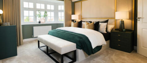 Stylish bedroom with a large bed, green and white bedding, matching nightstands, and natural light f
