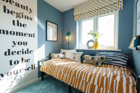 A cozy and vibrant bedroom with a patterned bedspread, a wall decal with an inspirational message