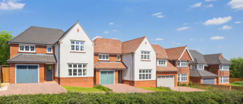 Modern suburban houses with brick and white exteriors, pitched roofs, and front driveways under a bl
