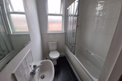 A bright and clean bathroom featuring a bathtub...