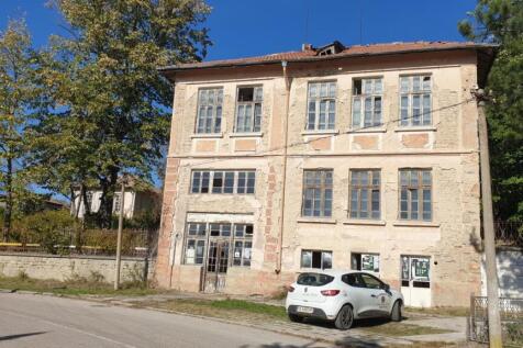 Front facade of school building with a white car parked outside under blue sky