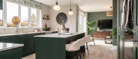 Modern open-plan kitchen and living room with green cabinets, white marble countertops, and a cosy s