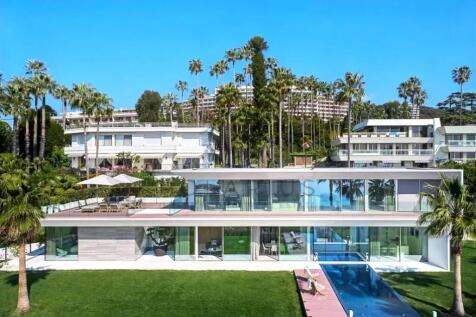 A modern, glass-fronted two-story house with a poo