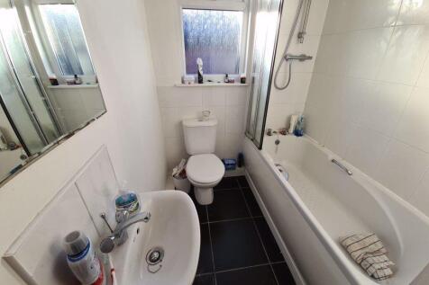 A clean and bright bathroom featuring a bathtub...