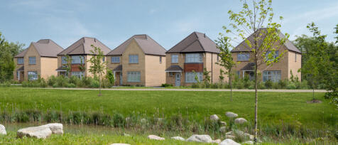 A row of modern brick houses with pitched roofs set against a clear sky, surrounded by green lawns,