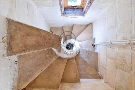 A spiral staircase with a stone texture is viewed