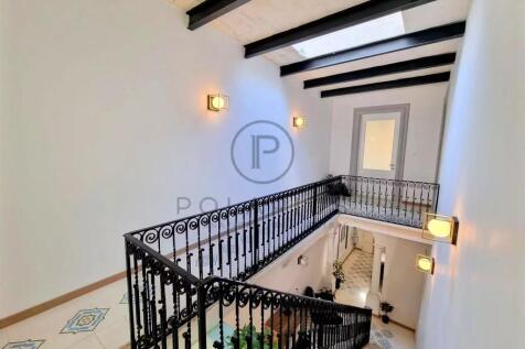 A bright staircase with black wrought iron railing
