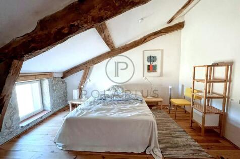 This cozy attic bedroom features a wooden beam cei