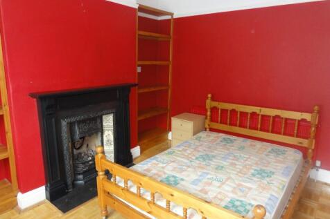 A cozy double bedroom featuring warm red walls,...
