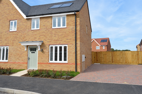 A modern two-story brick house with a light green door stands in the foreground