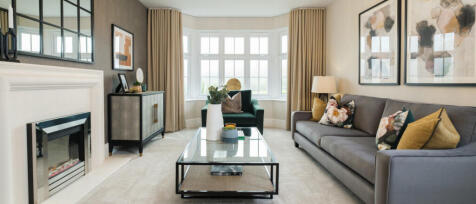 Modern living room with bay window, grey sofa with floral and mustard cushions, fireplace, and conte