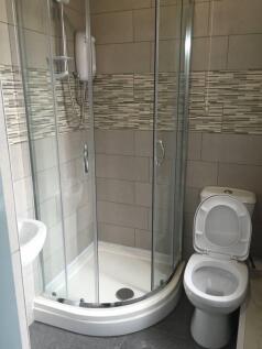 Modern tiled bathroom with a curved glass showe...