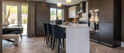 Stylish open plan kitchen with large island and bar stools with modern dark design