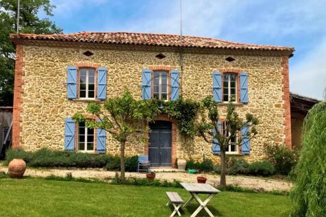 A charming stone house with blue shutters, surroun