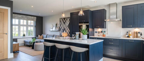 Modern open-plan kitchen and living room with navy blue cabinets, a white island, beige seating, and