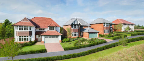 A row of modern detached houses with red and grey tiled roofs, set on a landscaped hillside in Dares