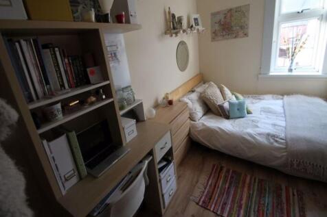 A cozy student bedroom featuring a bed and a bo...