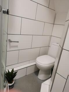 Bright, modern bathroom with large white tiles,...