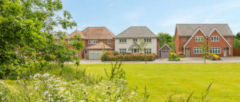 Three modern detached houses with well-maintained lawns and trees in a suburban neighbourhood under