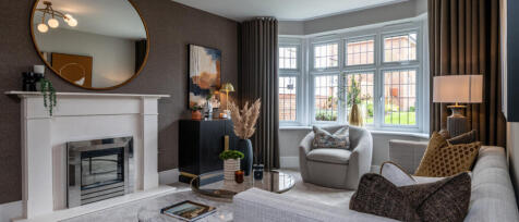 Contemporary living room with a white fireplace, large bay window, beige sofa, armchair, and elegant