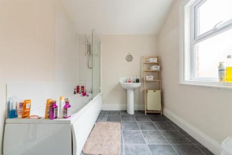 A bright and spacious bathroom featuring a bath...