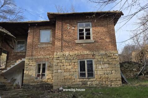 Exterior view of a two-storey house showing stone and brick walls with several windows and an outdoor staircase