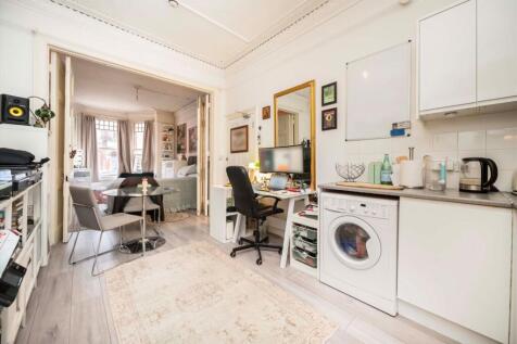 The accommodation at raised ground floor level comprises a very spacious bedroom with bay-fronted windows and high ceiling, a living/dining area with open plan kitchen and a small conservatory/utility