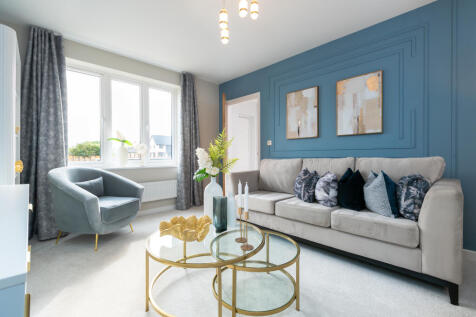 A plush gray sofa with decorative pillows sits in front of a blue accent wall with framed art