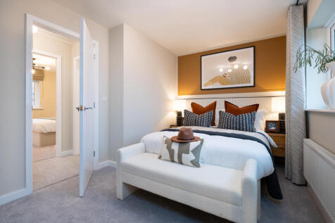 A white bench sits at the foot of a bed with a patterned accent wall in the background