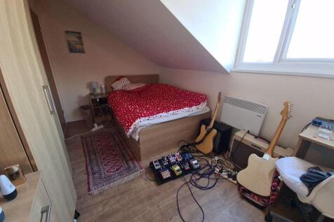 A cozy single bedroom featuring a bed with a re...