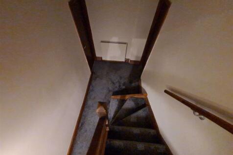 A narrow staircase with carpeted steps and wood...