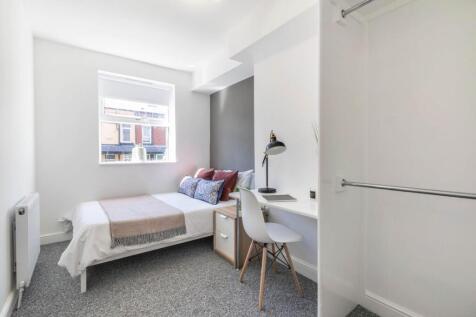 A bright and tidy bedroom featuring a comfortab...