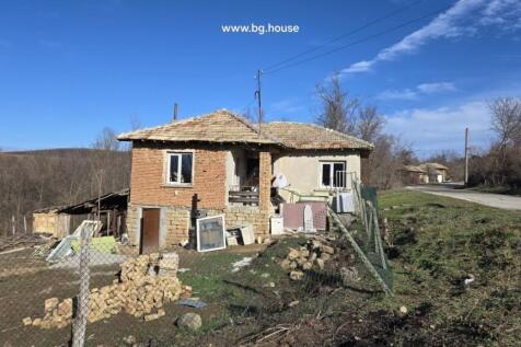 Exterior view of a traditional Bulgarian house showing stone lower walls and brick upper walls with a tiled roof
