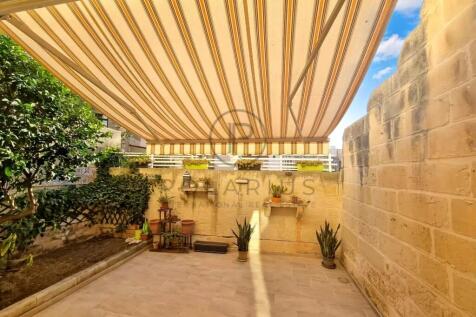 A sunlit patio with a striped awning, potted plant