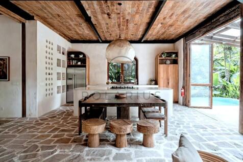 A rustic kitchen with a wooden ceiling, a central