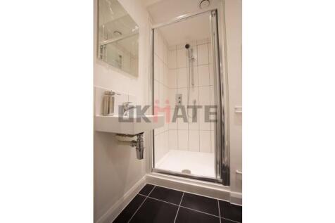 A modern, clean bathroom featuring a glass-encl...