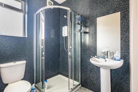 Bright, modern bathroom with a corner glass sho...