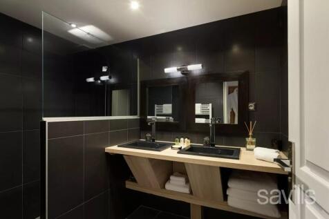 A modern bathroom with dark tiles features two sin