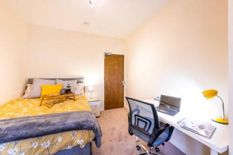 Bright, neatly furnished bedroom with a comfy d...