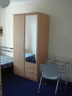 A small student bedroom featuring a wooden ward...