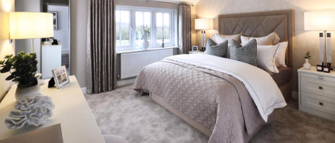 A cosy bedroom with a large bed, neutral tones, and a window with curtains overlooking a green lands