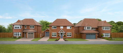 Three modern brick detached houses with driveways and front gardens under a blue sky, surrounded by
