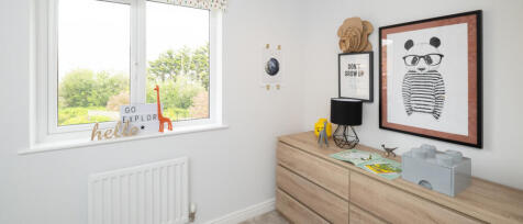 A bright children&#39;s bedroom with a wooden dresser, panda artwork, toys, books, and a window showing