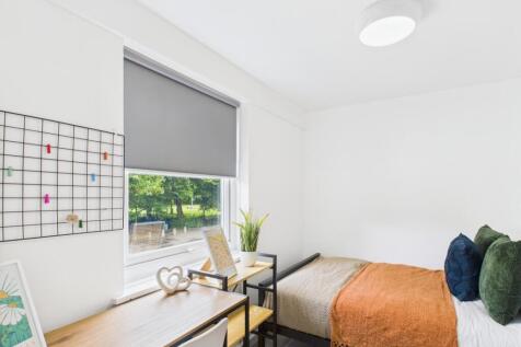 Bright, neatly presented bedroom with a study d...