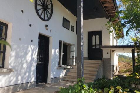 White exterior wall of the house featuring black doors, windows, and a decorative wooden wagon wheel