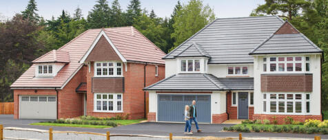 Two people walking in front of a modern semi-detached house with a red brick and white exterior, sur