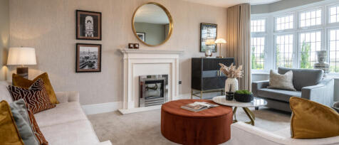 Modern living room with beige walls, large bay window, grey sofas, a fireplace, and decorative cushi